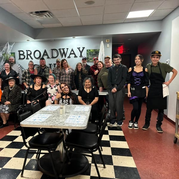 Broadway FAMILY Grill staff in Halloween costumes pose together in the dining area.
